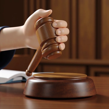 A close-up of a judge's hand with a light skin tone gripping a wooden gavel firmly. The gavel is made of polished wood with a smooth finish, reflecting light. In the background, there are blurred hints of a courtroom setting, with wooden paneling and a hint of a bench visible. The judge's hand is adorned with a simple silver ring. The focus is on the gavel, emphasizing its importance as a symbol of justice.