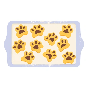 A rectangular tray filled with freshly baked cookies shaped like dog paws. Each cookie has a golden-brown color with slightly darker edges. The cookies are arranged neatly, some with chocolate chips placed in the center of each paw print. A light dusting of powdered sugar covers the surface of the tray, adding a touch of sweetness. The background features a soft, light-colored kitchen countertop.