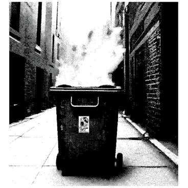 A dumpster is positioned in an urban alleyway, with its lid slightly ajar as if it is alive. Flames are erupting from the opening at the top, creating a fiery glow that illuminates the surrounding area. The flames twist and curl, resembling the breath of a dragon. The metal surface of the dumpster is rough, showing signs of wear with dents and scratches. Shadows cast by the flickering fire dance on the brick walls of the alley, enhancing the dramatic atmosphere of the scene.