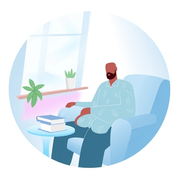 A person with a bald head is sitting in a sunlit room. The individual is wearing a patterned shirt with intricate designs. Sunlight is streaming through a large window, casting soft shadows on the warm wooden floor. There are potted plants on the window sill that add a touch of greenery to the scene. A few books are neatly arranged on a table beside the individual. A comfortable, textured chair is where the person is seated, creating a cozy atmosphere in the room.