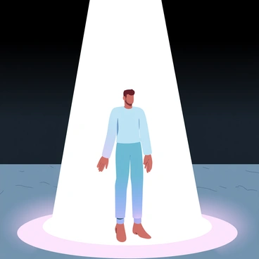 A person is standing alone in the center of an empty stage, illuminated by a bright spotlight. The surrounding area is dark, emphasizing the isolation of the figure. The person is wearing a simple outfit, with hands at their sides. The spotlight creates a sharp contrast between light and shadow, highlighting the contours of their body. The stage is bare, with only a wooden floor visible beneath the spotlight. The atmosphere reflects a sense of vulnerability and exposure.