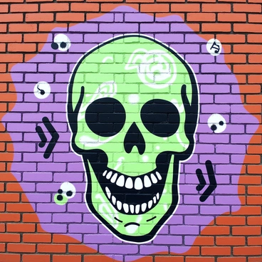 A skull is prominently displayed on a brick wall, intricately painted with a graffiti style. The skull features exaggerated contours and details, adorned with various designs and patterns. Surrounding the skull, the brick wall provides a textured backdrop, each brick clearly defined with its own unique shade. The mural captures the essence of urban art, with splashes and strokes that highlight the skull's features and create a striking visual impact.