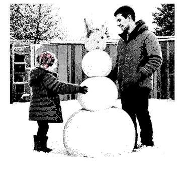 A big brother is standing beside a little sibling in a snowy backyard. The big brother has short hair and is wearing a thick winter jacket and a knitted hat. He is smiling as he shapes a large snowball, stacking it on top of another snowball. The little sibling, with pigtails and a colorful scarf, is bending down to roll a smaller snowball, adding it to the base. Their footprints are visible in the snow, leading to the partially built snowman, which has a carrot for a nose and sticks for arms. In the background, there are trees covered in snow.