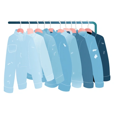 A clothing rack is filled with various styled denim jackets hanging. Each jacket displays different designs, including distressed, embellished, and classic cut styles. The jackets feature a range of colors from light blue to dark indigo. Each piece is carefully arranged to showcase the unique textures and stitching details. The background is softly illuminated, enhancing the visual appeal of the denim fabrics.