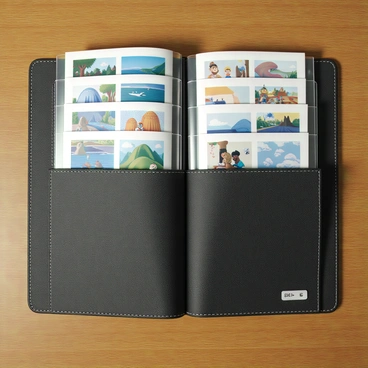 A portfolio binder made of black leather with a textured surface, opened to reveal several transparent plastic sleeves. Each sleeve contains a colorful illustration sample, showcasing a variety of styles and subjects, such as landscapes, characters, and abstract designs. Each illustration has a small price tag positioned neatly in the lower corner, printed in clear, legible text. The binder is resting on a wooden table with soft lighting highlighting the samples, creating a professional and inviting presentation.