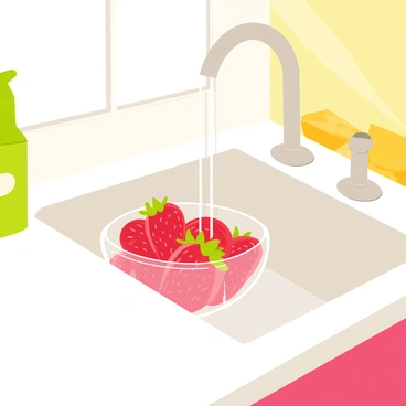 A kitchen scene featuring a bright and clean countertop with a white sink. A bowl filled with fresh, red strawberries is placed in the sink, water cascading over the strawberries. The bowl is transparent, showing the vibrant colors of the strawberries inside. Surrounding the sink are various kitchen items, including a green dish soap bottle and a yellow sponge. Sunlight streams through a nearby window, illuminating the scene and highlighting the glossy texture of the strawberries.