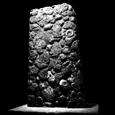An ancient stone wall stands tall within a dark chamber. The surface of the wall is rough and irregular, showcasing weathered stones that vary in size and texture. Glowing, cryptic symbols are etched into the stone, appearing luminous against the dark background. The symbols have intricate designs, some resembling spirals and others depicting shapes, all surrounded by deep shadows that enhance their brightness. The overall atmosphere of the chamber is mysterious and enigmatic, with the faint glow of the symbols providing the only light source.