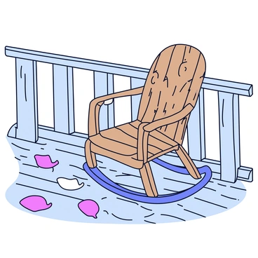A timeworn rocking chair made of weathered wood is placed on a porch. The chair has a slightly curved design with visible signs of aging, such as cracks and a faded finish. Scattered around the base of the chair are fallen petals in various shades of pink and white, creating a soft, colorful carpet on the wooden porch floor. The surrounding area is framed by the railing of the porch, which has a rustic appearance.