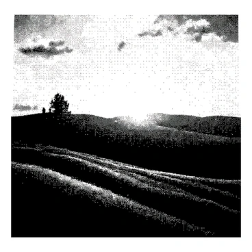 A landscape featuring rolling hills under a sunset sky. The hills are gently sloping and provide a sense of depth and dimension. The sun is low on the horizon, casting long shadows across the terrain. The clouds in the sky are scattered, reflecting the soft light of the setting sun. A few trees are positioned on the hills, their silhouettes outlined against the sky. The overall composition creates a tranquil scene with a focus on the natural beauty of the landscape.