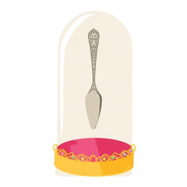 An antique fourchette made of silver is displayed under a glass dome. The fourchette has intricate engravings along its handle, showcasing detailed floral patterns. Surrounding the dome are ornate decorative elements, including golden filigree and small, colorful gemstones embedded in a rich velvet base. The overall composition highlights the elegance of the fourchette while emphasizing the luxurious surroundings.