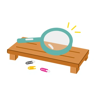 A clear magnifying glass with a circular lens rests on a wooden table. The lens is slightly distorted by the table's grain, emphasizing its transparency. Underneath the magnifying glass, the surface of the table is polished, reflecting light in a subtle way. The magnifying glass remains stationary, illustrating the concept of static friction. A few small paper clips are scattered nearby, hinting at the context in which the glass is being used. The overall composition captures the relationship between the magnifying glass and the surface it's resting on.