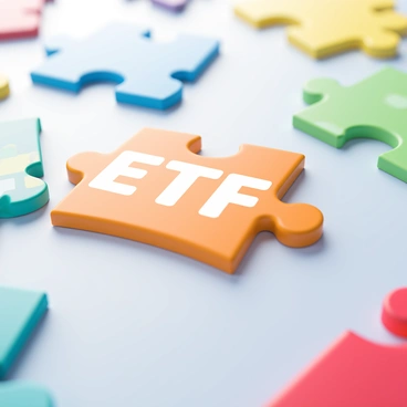 A close-up view of colorful puzzle pieces coming together on a light surface. One prominent puzzle piece features the letters "ETF" clearly displayed in bold, white font. Surrounding this piece are various other puzzle pieces in vibrant colors such as blue, green, and red, each with unique patterns. The light source casts soft shadows, emphasizing the texture of the pieces and the gradual alignment as they fit together.