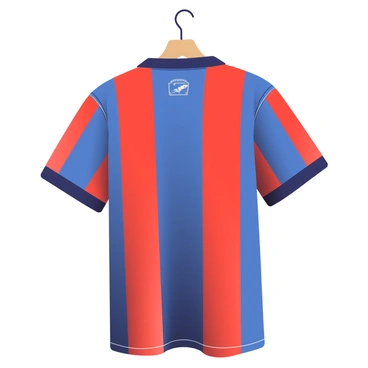 A vintage soccer jersey from the 1970s is displayed prominently in the foreground. The jersey features a classic striped design with bold colors, including deep blue and bright red stripes alternating across the fabric. The collar is a simple round design, and the sleeves are slightly oversized, reflecting the fashion of that era. The fabric has a slightly worn texture, hinting at its age, and the back has a small logo stitched in white thread. The jersey is hanging on a wooden hanger against a soft, neutral background to emphasize the vibrant colors.