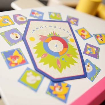 A close-up of a "legendary Pokémon card" placed in the center of the image. The card showcases intricate designs and vibrant colors, giving attention to its unique features such as holographic elements and detailed artwork. Surrounding the legendary card are smaller "regular Pokémon cards" arranged in a circular pattern. Each regular card displays a different Pokémon, with varying colors and designs, contributing to an overall dynamic composition. The background is softly blurred to emphasize the legendary card in the foreground.