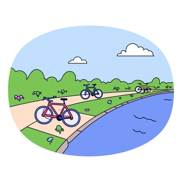 A scenic riverside path lined with lush green grass and wildflowers. The path is made of smooth, light-colored stones, leading alongside the gently flowing river. Several bicycles are parked along the water's edge, positioned on a small grassy area. The bikes are in various colors, including red, blue, and yellow, with their front wheels gently leaning against the ground. The water reflects the clear blue sky and a few fluffy white clouds drifting above.