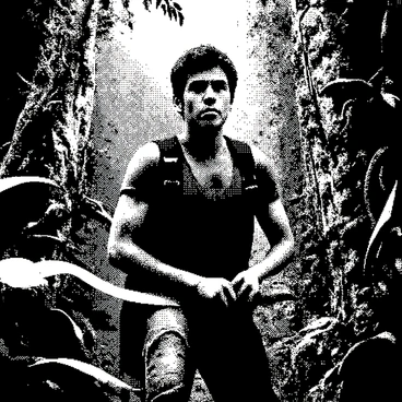 An explorer with short brown hair is wearing a rugged outfit suitable for jungle exploration. He is in the midst of dense jungle foliage, surrounded by large green leaves and intertwined vines. The explorer is wielding a machete and is actively hacking through the vegetation, showing determination on his face. In the background, partially obscured by the trees, are the outlines of mysterious ruins that hint at ancient architecture, with stone structures covered in moss and creeping plants. Sunlight filters through the canopy, casting dappled shadows on the ground.