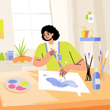 An artist with curly hair is carefully applying soft blue and green watercolors to a sheet of white paper on a wooden table. The studio is filled with various paintbrushes and jars of water, with splashes of paint on the table surface. Light streams in through a large window, illuminating a small potted plant on the windowsill. A colorful palette rests beside the artist, showcasing vibrant hues. The walls of the studio are lined with framed artworks, adding an inspiring touch to the scene.