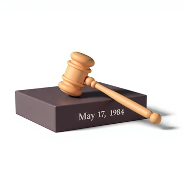 A wooden judge's gavel, polished and gleaming, is resting on a rectangular sound block. The sound block has a smooth finish and is made from dark mahogany, contrasting with the lighter wood of the gavel. Engraved on the sound block is the date "May 17, 1954," prominently displayed in an elegant font. The background is softly illuminated, highlighting the details of the gavel and the sound block.