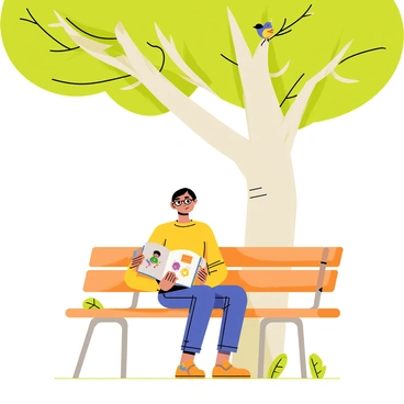 A person with short brown hair wearing glasses sits on a wooden park bench under a large green tree with broad, leafy branches. The individual is holding an open book with colorful illustrations, completely absorbed in the reading. Sunlight filters through the leaves, casting dappled light and shadows on the ground. A few birds can be seen perched on the tree branches nearby, adding life to the serene park setting. A gentle breeze causes some leaves to flutter down around the bench.