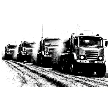 A group of trucks, each featuring a distinctive brick-patterned design, is speeding across a rugged dirt track. The trucks are of various sizes, showcasing different shapes and functionalities. Dust is being kicked up from the ground, creating a dynamic atmosphere. In the background, there are hints of trees and hills, adding depth to the scene. The trucks have their headlights on, illuminating the path ahead as they compete against each other.