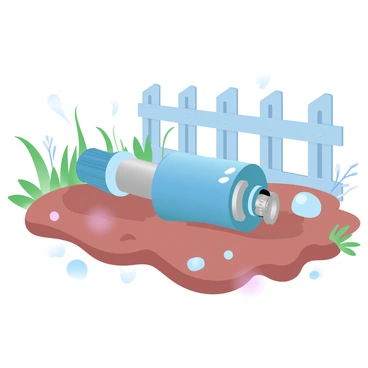 A toy robot is lying on its side in a patch of dirt. The robot is metallic blue and silver, with visible gears and small lights that appear dim. Surrounding the robot are patches of grass and small weeds, suggesting a neglected area. Various small stones and twigs are scattered around it. In the background, a faded wooden fence is partially visible, adding to the sense of abandonment in the corner of the yard.