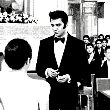 A man resembling Elvis Presley, with slicked-back dark hair and wearing a formal black tuxedo, is standing at a wedding ceremony. He has a confident expression on his face as he holds a ring in one hand, looking towards his partner. The setting features a decorated altar in the background, with floral arrangements enhancing the atmosphere. The guests seated nearby are attentively watching the moment. The entire scene captures the significance of the moment within the ceremony.