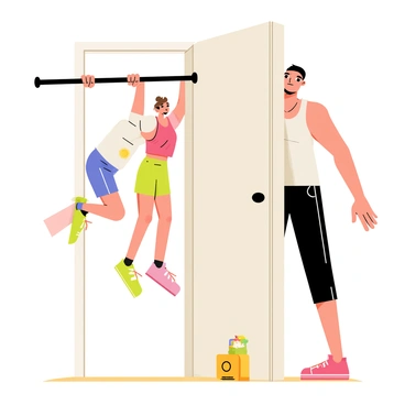 A young child with short brown hair is attempting to do pull-ups on a doorframe pull-up bar. The child is wearing a colorful t-shirt and shorts, with their feet barely off the ground. They have an expression of concentration as they pull themselves up. In the background, a parent is demonstrating the pull-up, showing an athletic build and wearing a tank top. The setting is a bright room with light-colored walls and a wooden floor, and a few toys are scattered around.