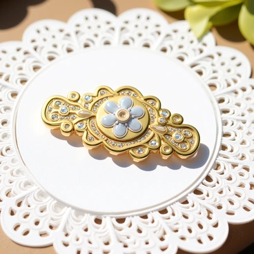 An ornate vintage brooch sits at the center of a delicate white lace doily. The brooch features intricate floral patterns in shades of gold and silver, with tiny gemstones embedded in the design. The lace doily has a scalloped edge and a fine weave, providing a contrasting texture to the smooth surface of the brooch. Sunlight casts soft shadows on the doily, highlighting the shimmering details of the brooch.